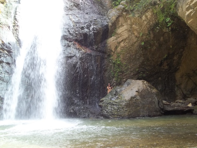 Rachel standing behind BIG rock at Salto de Baiguate Waterfall